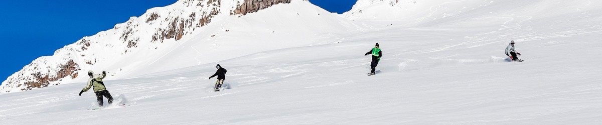 GROUP OF FOUR SNOWBOARDERS RIDING DOWN PALMER ON MT. HOOD