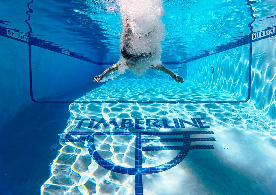 UNDERWATER PICTURE OF PERSON DIVING INTO THE TIMBERLINE POOL SHOWING THE TIMBERLINE LOGO AT THE BOTTOM OF THE POOL