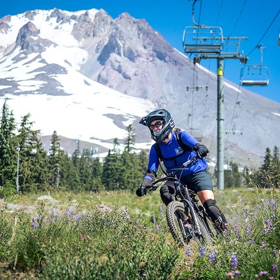 FEMALE MOUNTAIN BIKER IN BLUE RIDING THE TIMBERLINE BIKE PARK WITH MT HOOD IN THE BACKGROUND