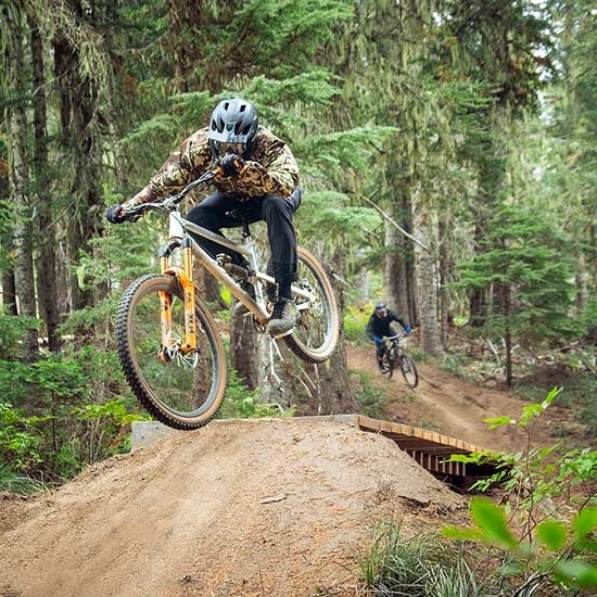 TWO MOUNTAIN BIKERS HITTING JUMPS AT THE TIMBERLINE BIKE PARK