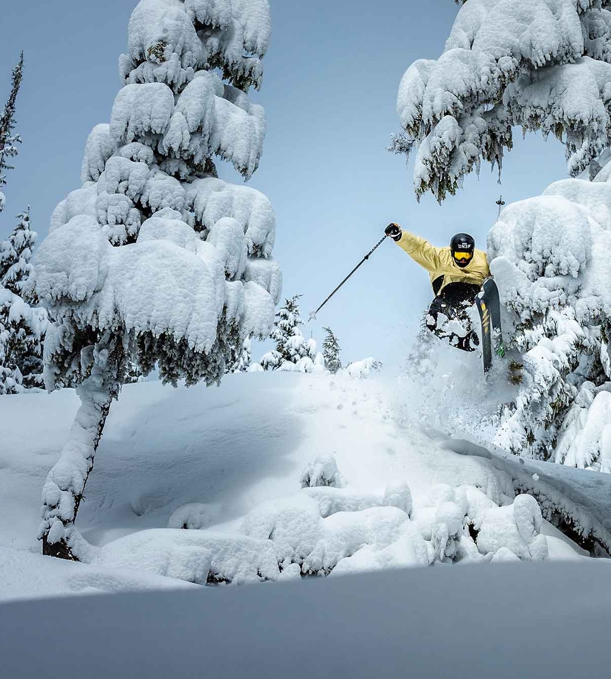 SKIER IN YELLOW JUMPING THROUGH DEEP POW TREES AT TIMBERLINE