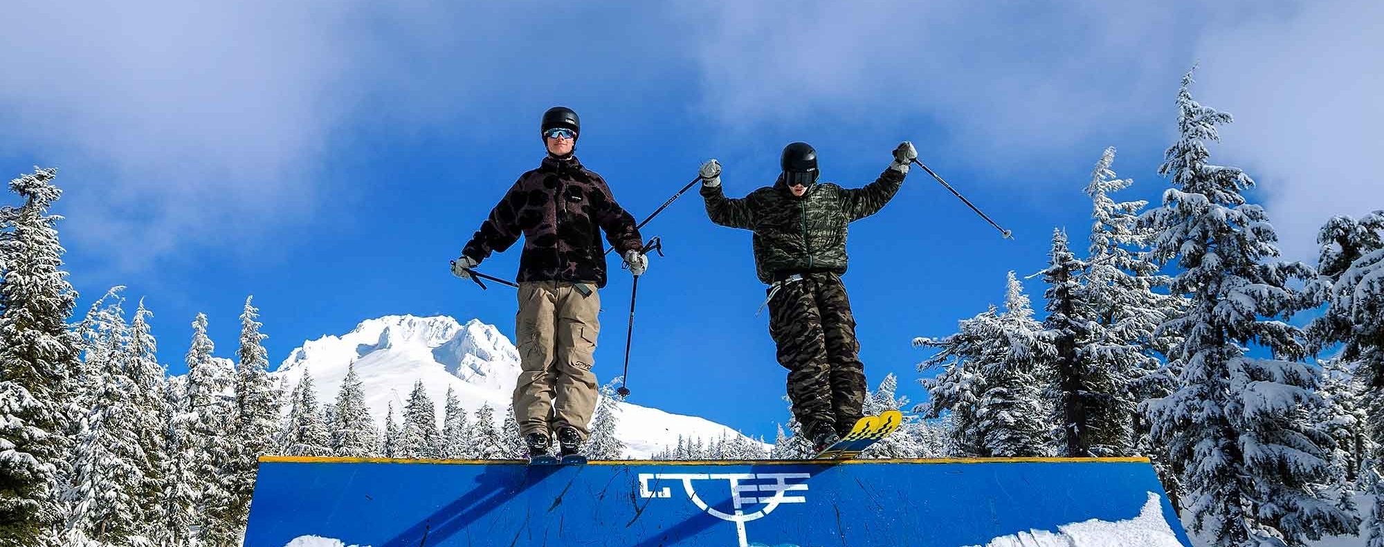 Two skiers on a feature at Timberline Lodge with Mt. Hood in the background