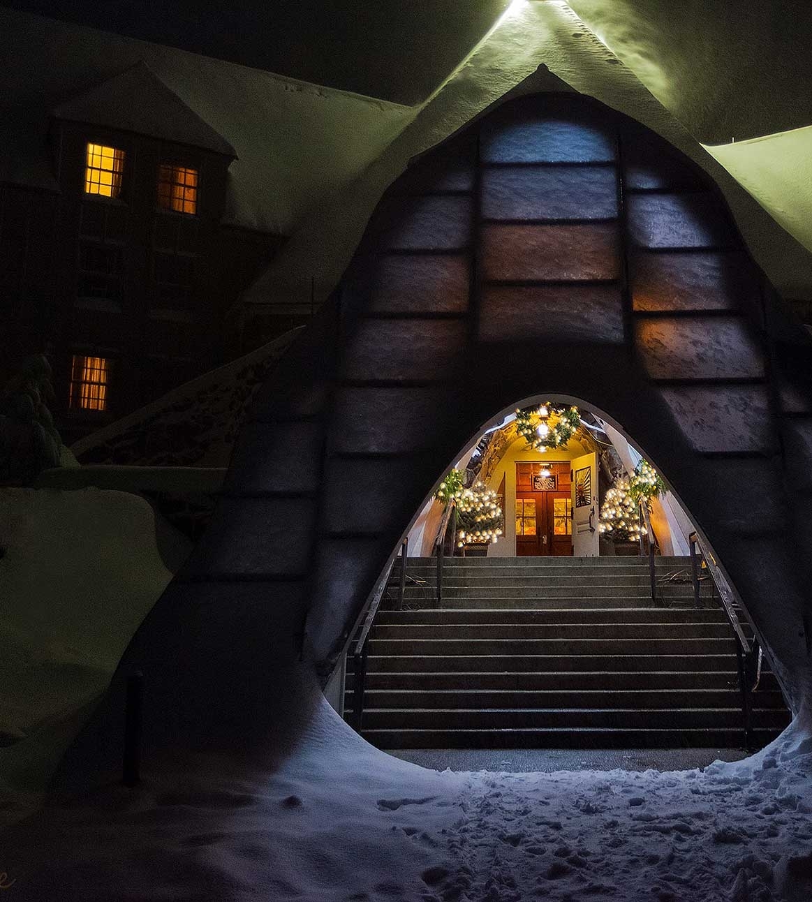 Timberline snow tunnel entrance decorated with garland and lights for the holidays, pictured on a dark and snowy night