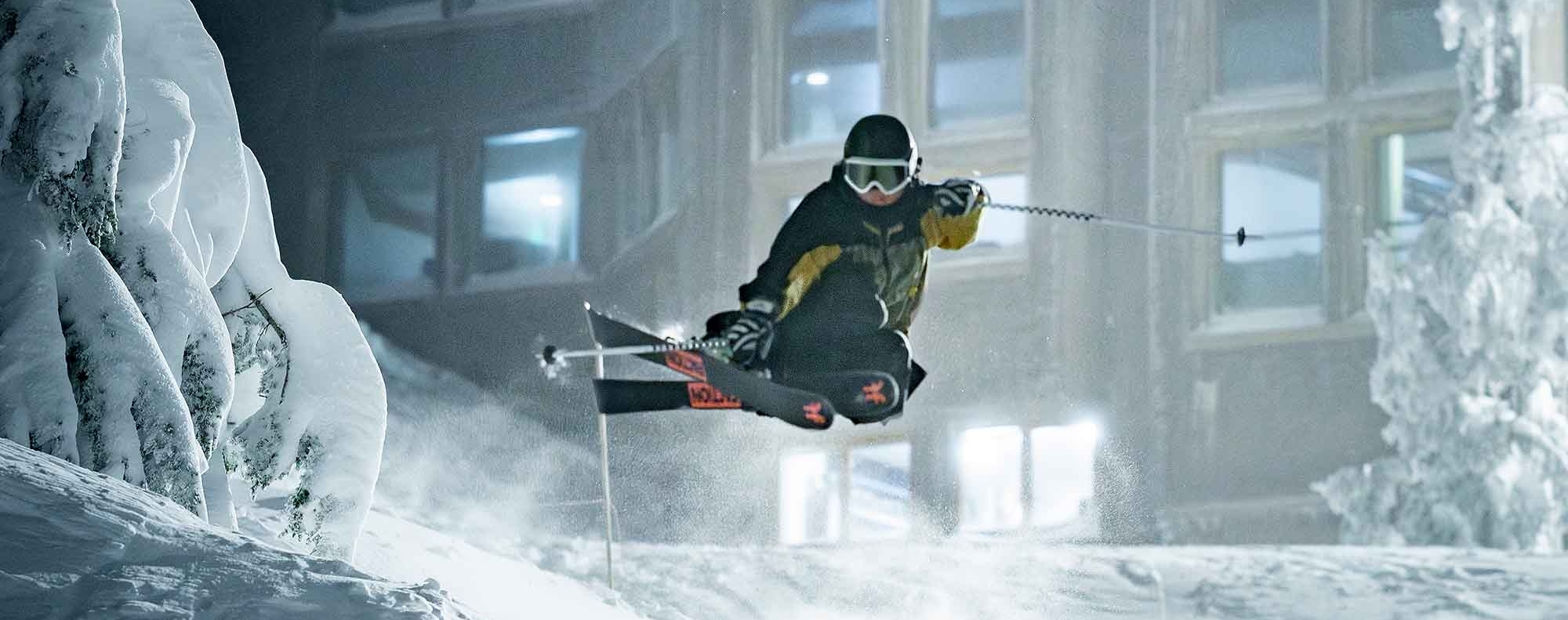 Skir doing a jump while night skiing at Timberline, Day Lodge pictured in the background