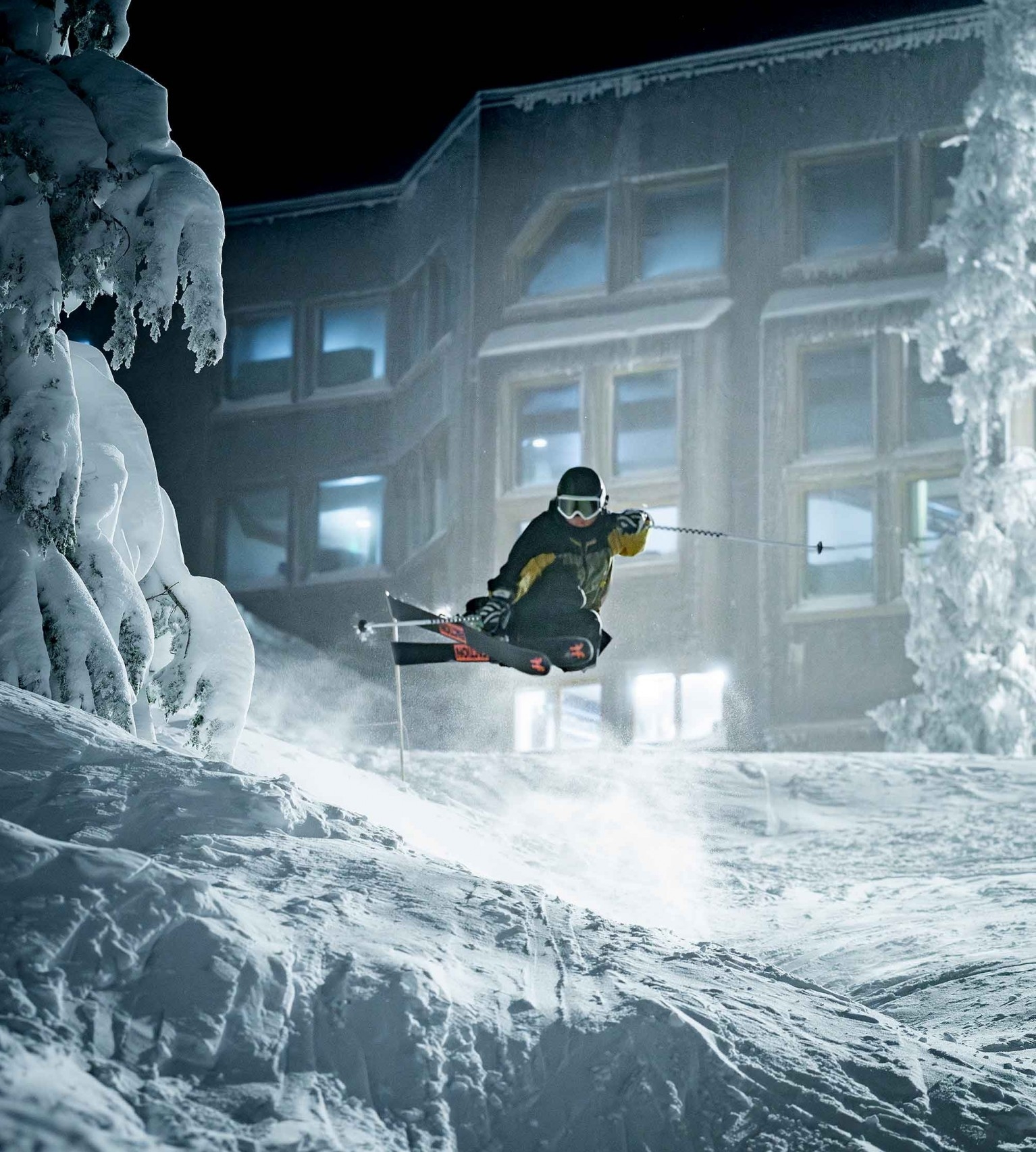 Skir doing a jump while night skiing at Timberline, Day Lodge pictured in the background