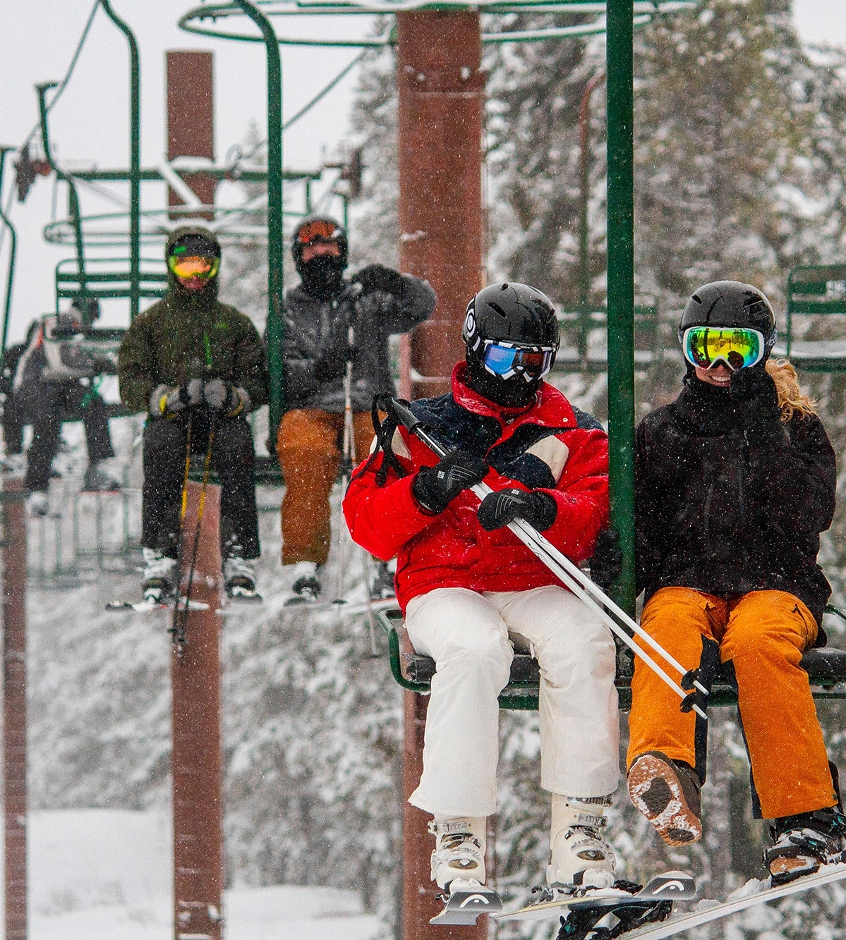 SKIERS RIDING A 2-PERSON CHAIRLIFT IN THE SNOW AT SUMMIT PASS