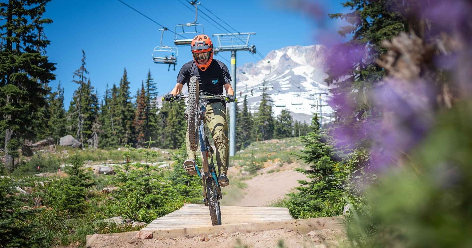 MOUNTAIN BIKER POPPING A WHEELY AT THE TIMBERLINE BIKE PARK ON MT. HOOD