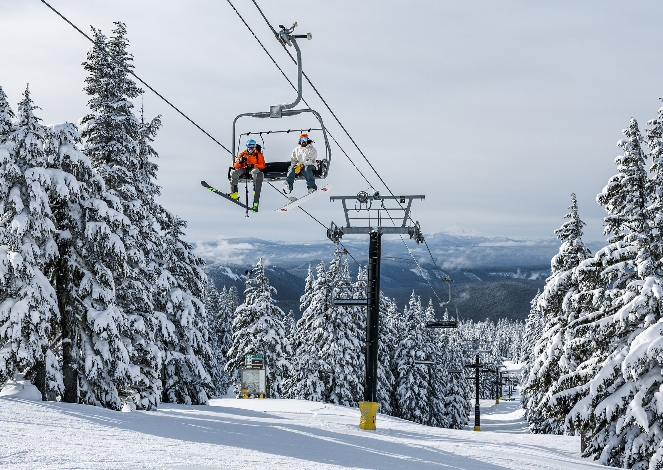 A skier and a snowboarder riding down Mt. Hood at Timberline