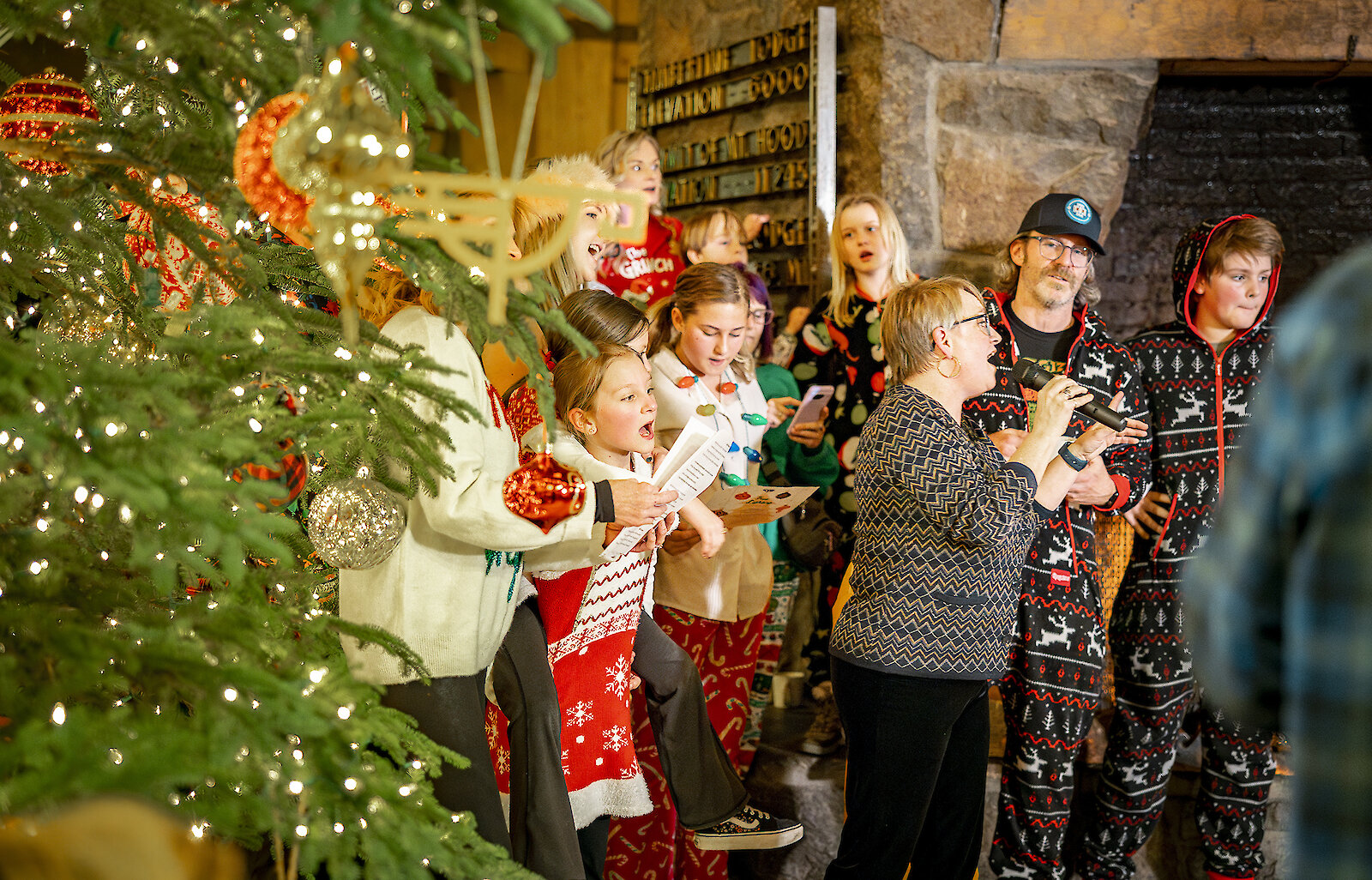 Timberline hotel guests singing Christmas carols around the holiday tree