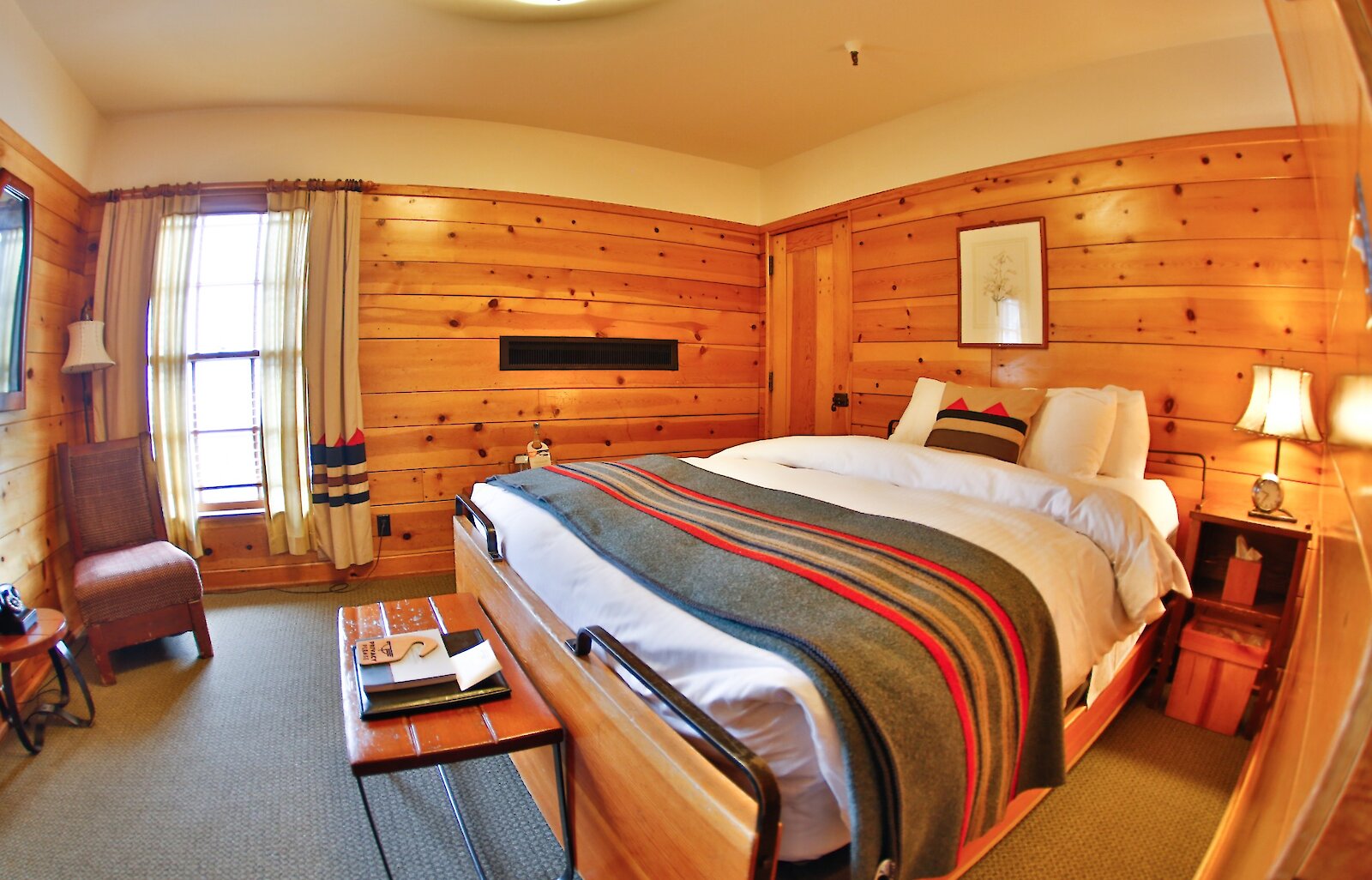 “Cozy Timberline Lodge guest room with a wood-paneled interior, neatly made bed, and soft natural light from the window.