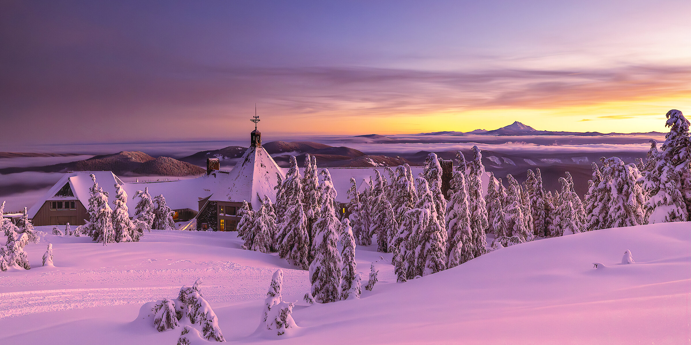 Snow-covered Timberline Lodge pictured at sunset overlooking Mt. Jefferson