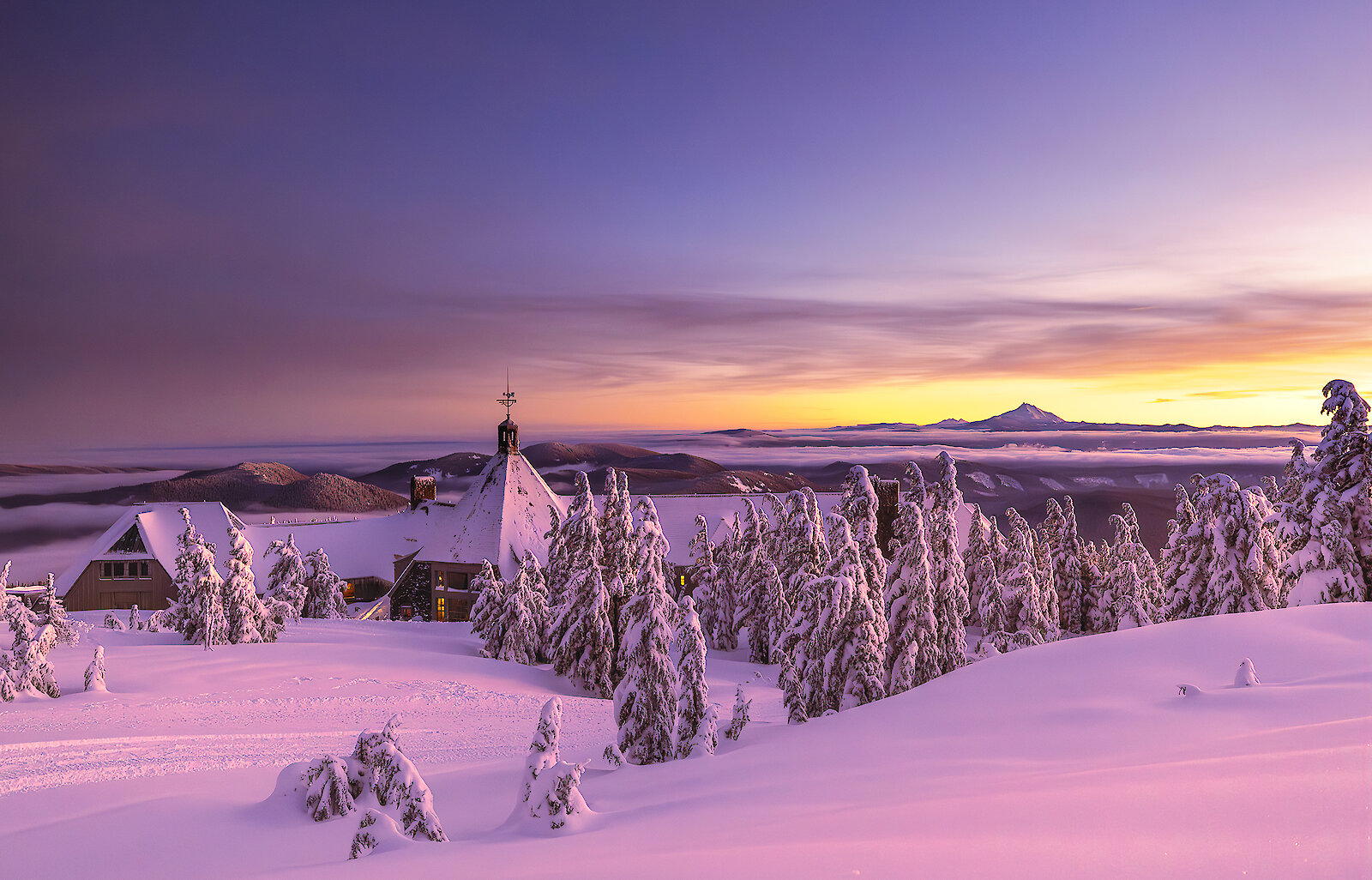 Snow-covered Timberline Lodge pictured at sunset overlooking Mt. Jefferson