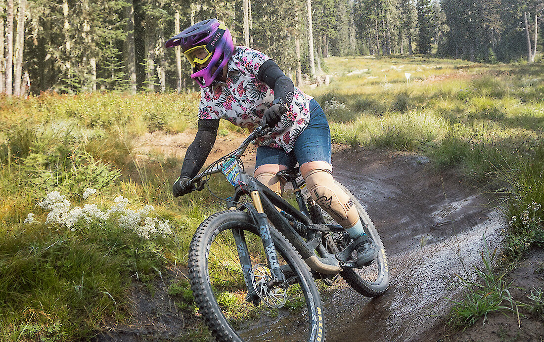 Downhill mountain biker carving a turn on a dirt trail through alpine forest at Timberline Lodge, Mount Hood.