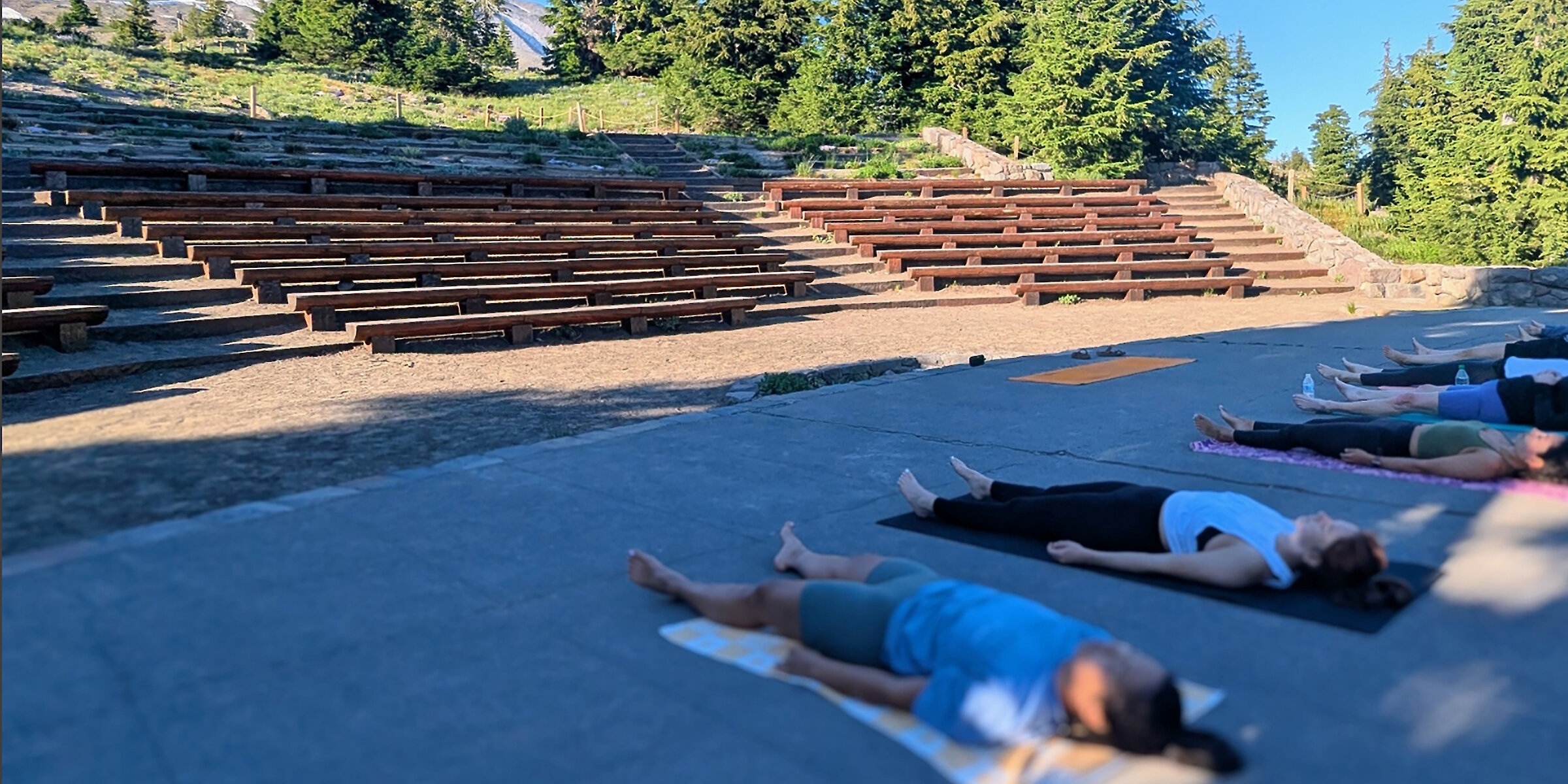 People laying on yoga mats in the Timberline amphitheater after a yoga session with Mt. Hood in the background