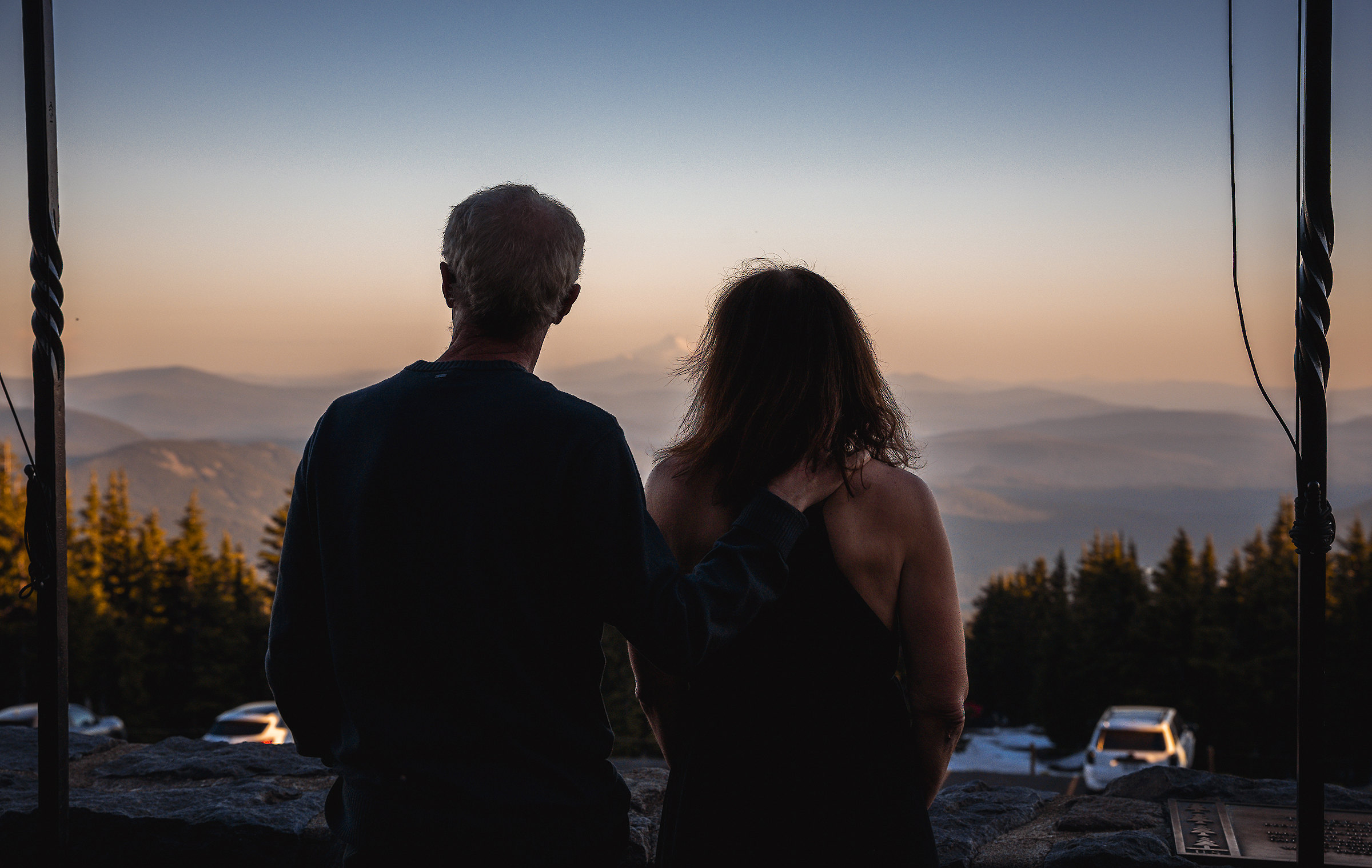 View from a behind a couple enjoying the views of the Cascades at sunset at Timberline