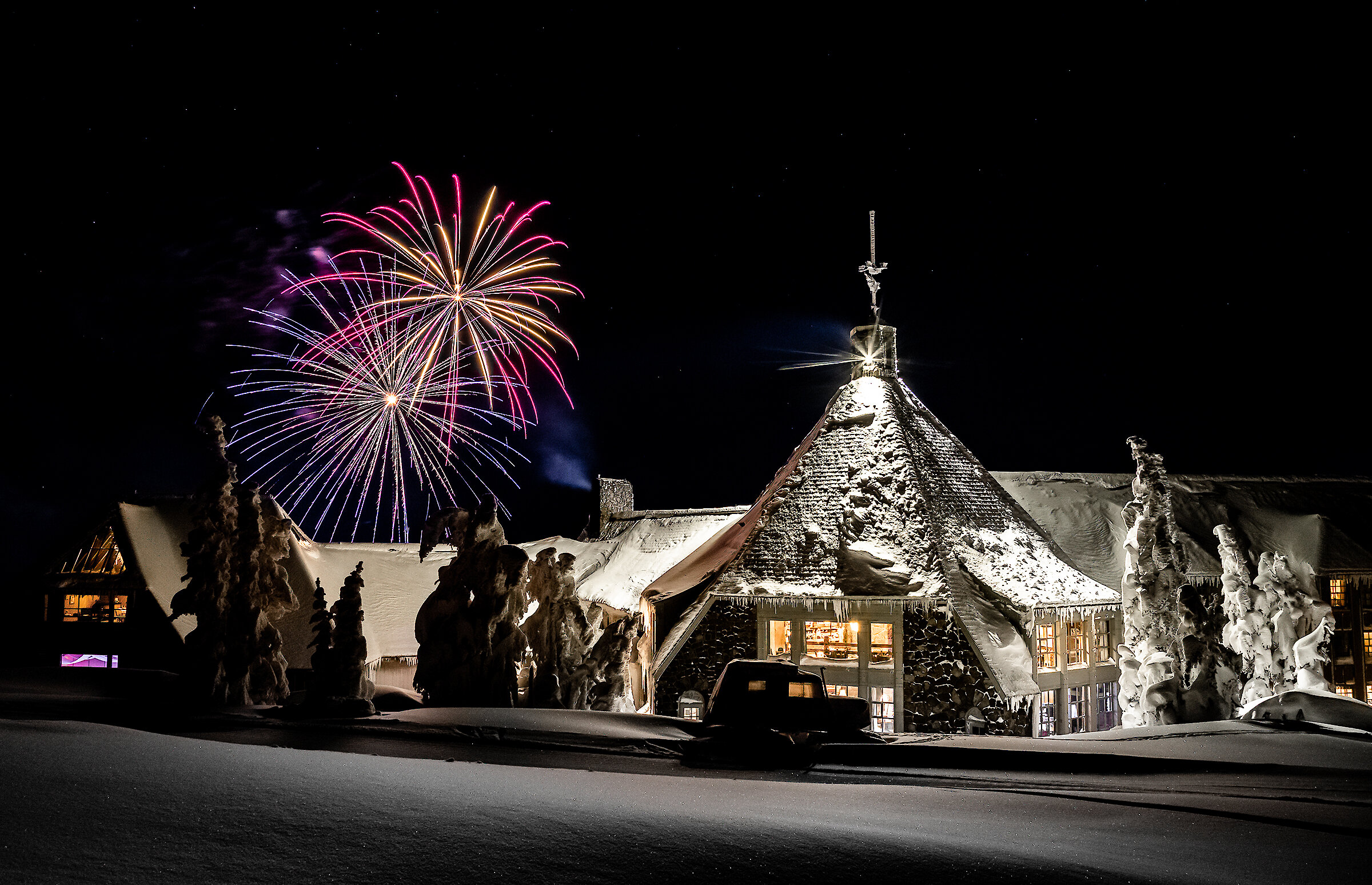 Snowboarder wearing tan gear and helmet jumps through snow-covered trees at Timberline Lodge, holding an orange snowboard midair above fresh powder.
