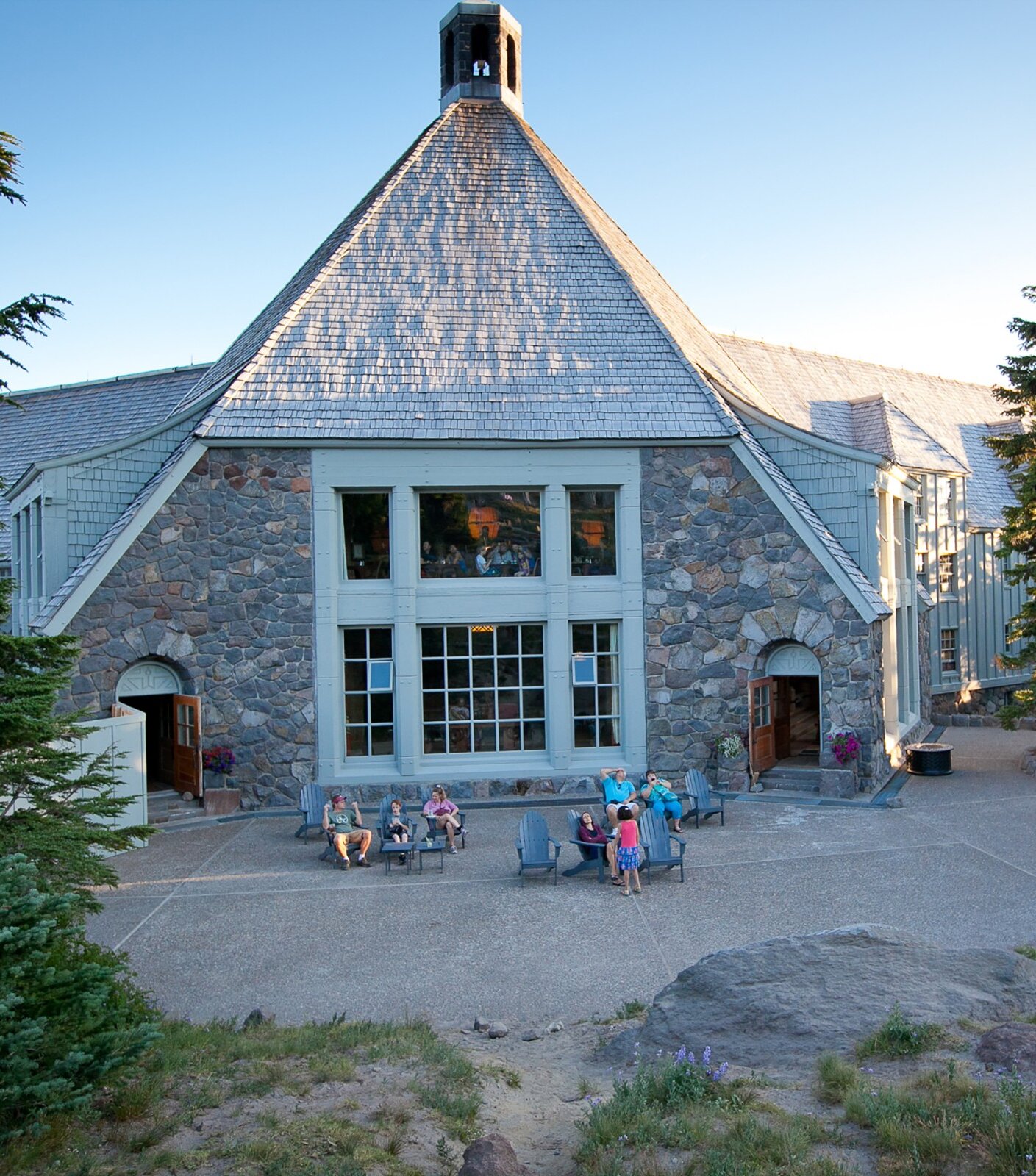 Daytime view of people enjoying the back patio at Timberline Lodge during the summer.