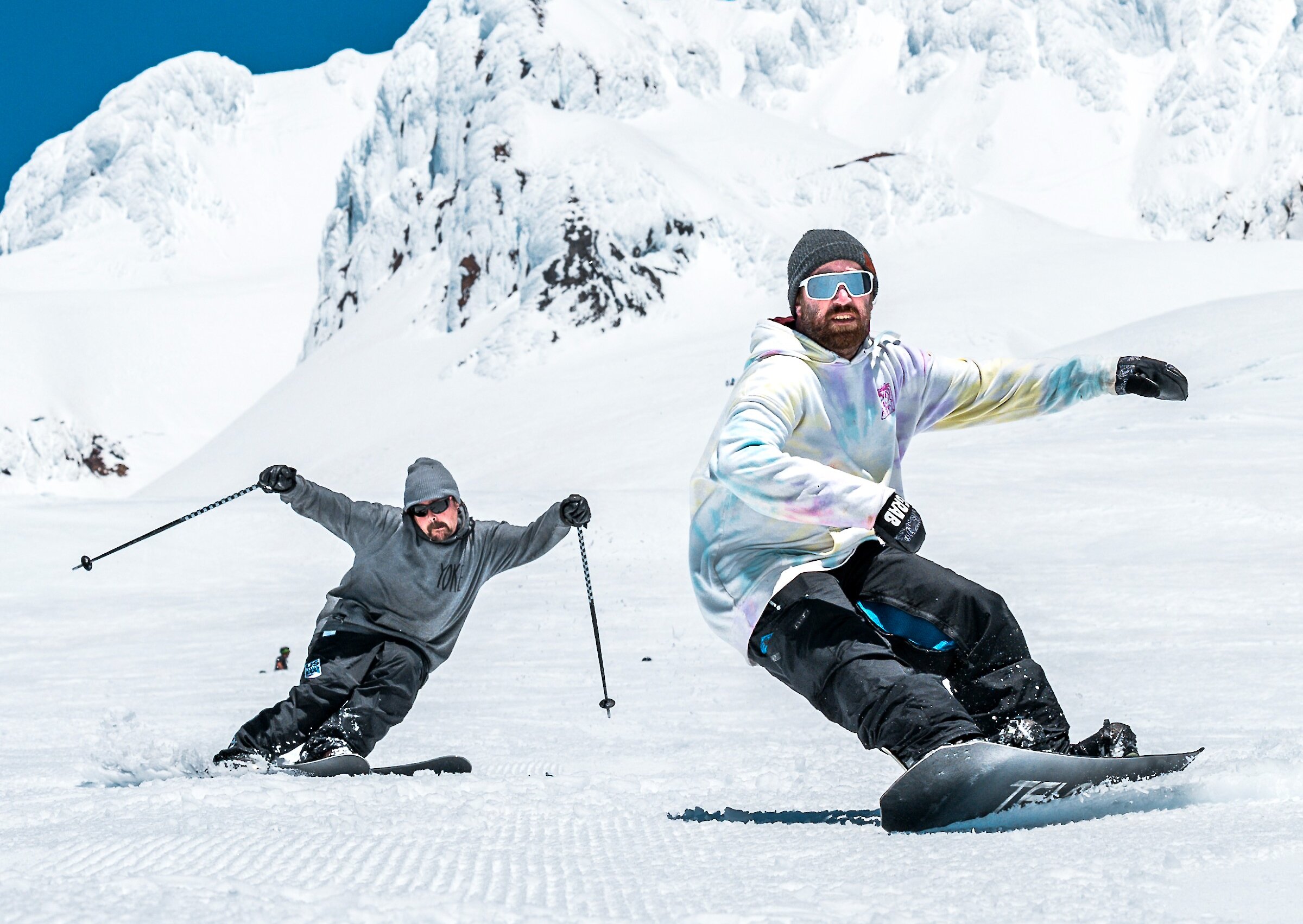 A skier and a snowboarder riding down Mt. Hood at Timberline