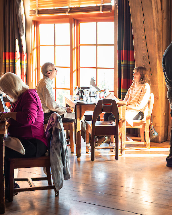 Guests enjoying lunch in the Cascade Dining Room at Timberline Lodge with a server taking orders by the sunlit windows.