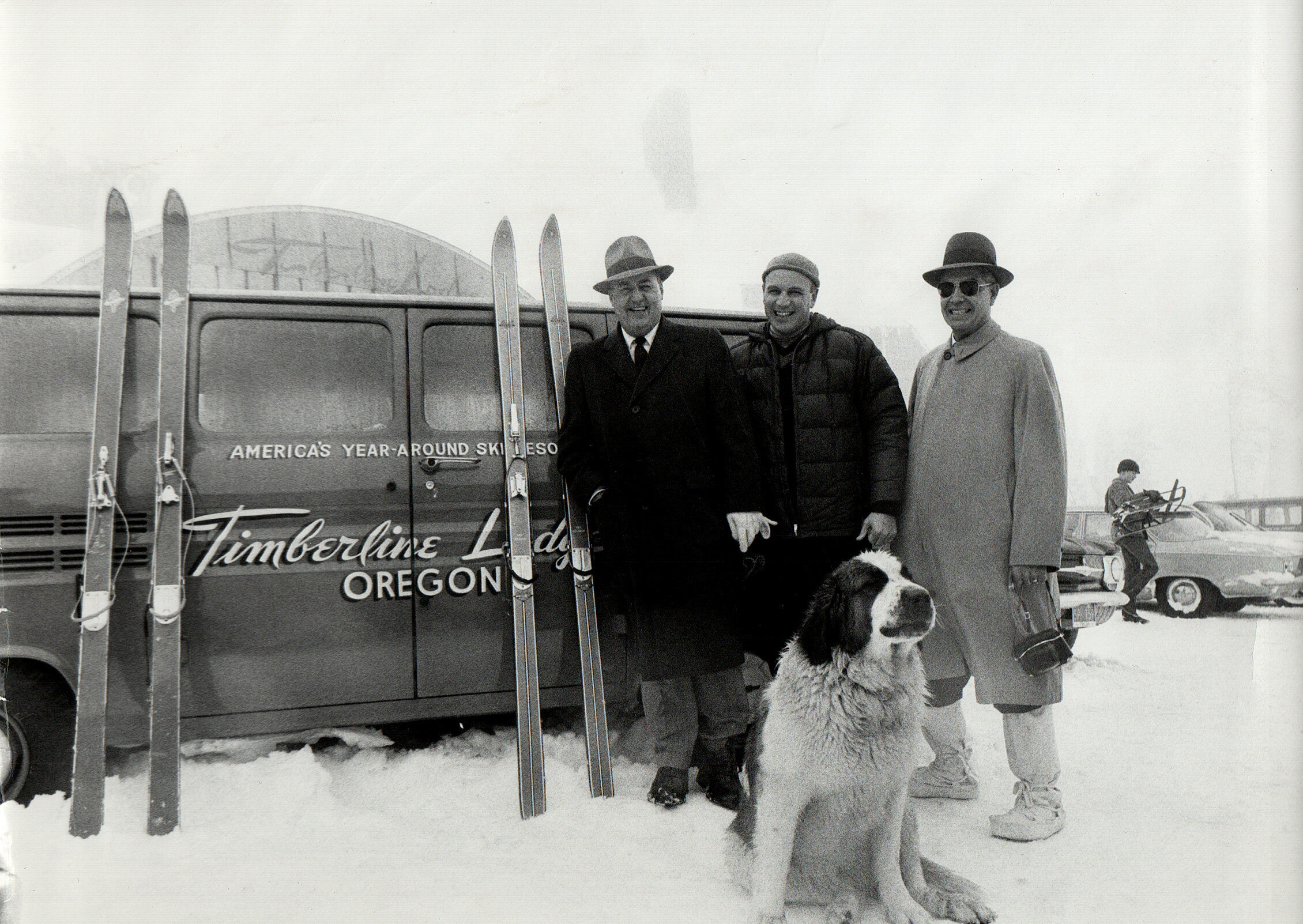 Richard Kohnstamm pictured in the 1960s with a St. Bernard and two other men in front of a van with the Timberline Lodge logo on it