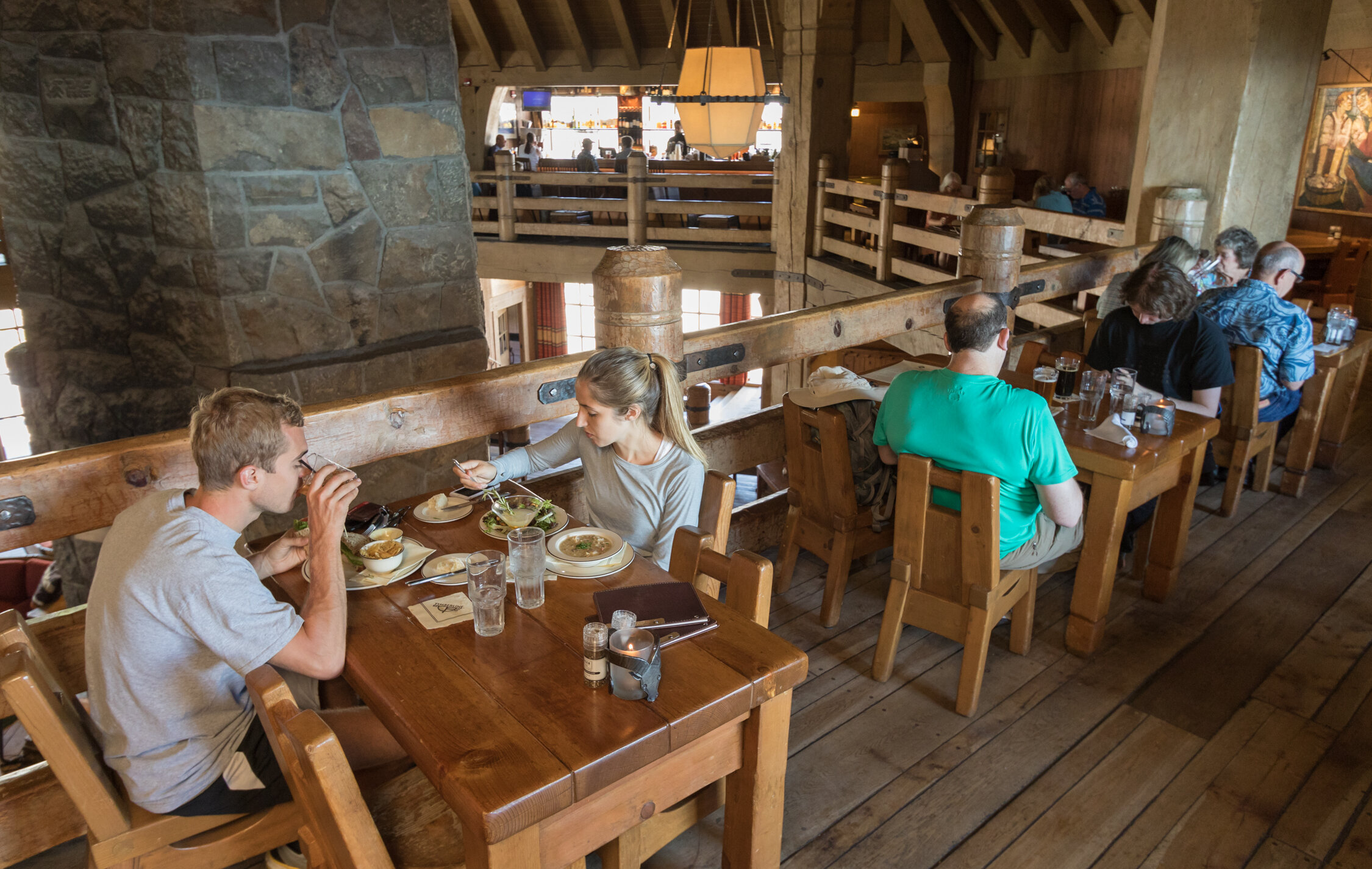 Couples dining around the mezzanine of the Ram's Head Bar, overlooking Timberline's Main Headhouse fireplace.