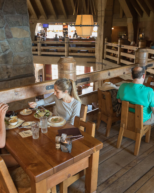 Couples dining around the mezzanine of the Ram's Head Bar, overlooking Timberline's Main Headhouse fireplace.