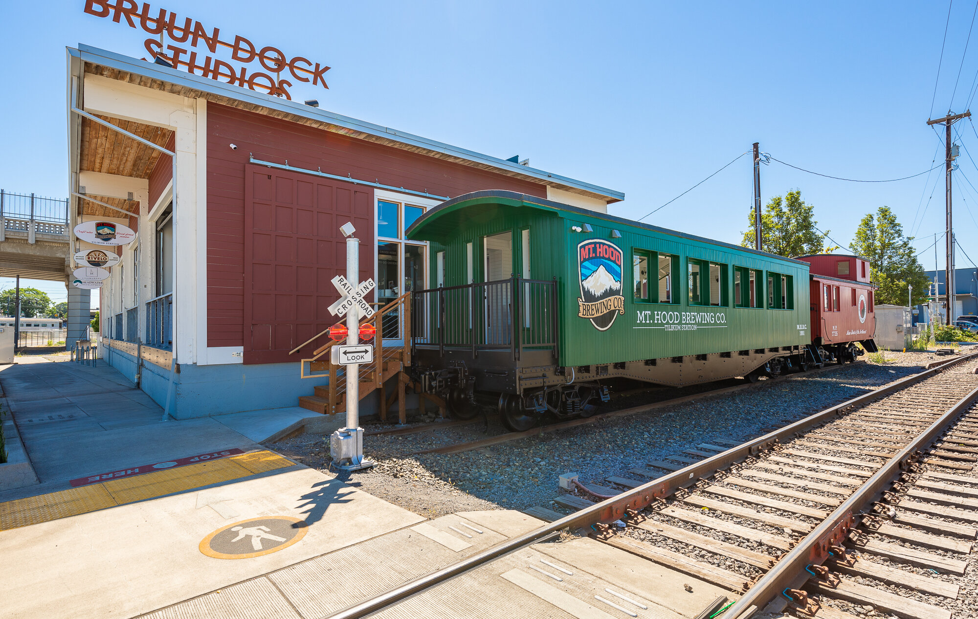 Mt. Hood Brewing Co. Tilikum Station green train car pictured beside the train tracks in Portland