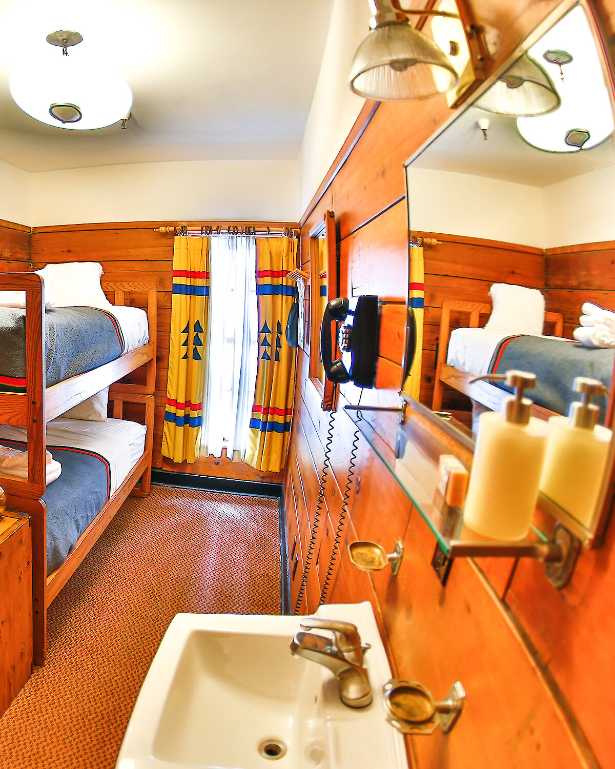 A small chalet room at Timberline Lodge features a bunk bed, sink, shelf, chair, and a window.