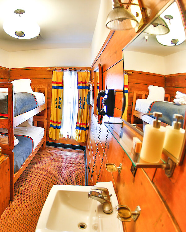 A small chalet room at Timberline Lodge features a bunk bed, sink, shelf, chair, and a window.