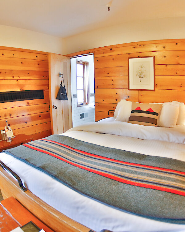 A Timberline queen room pictured with a Pendleton blanket draped over it.