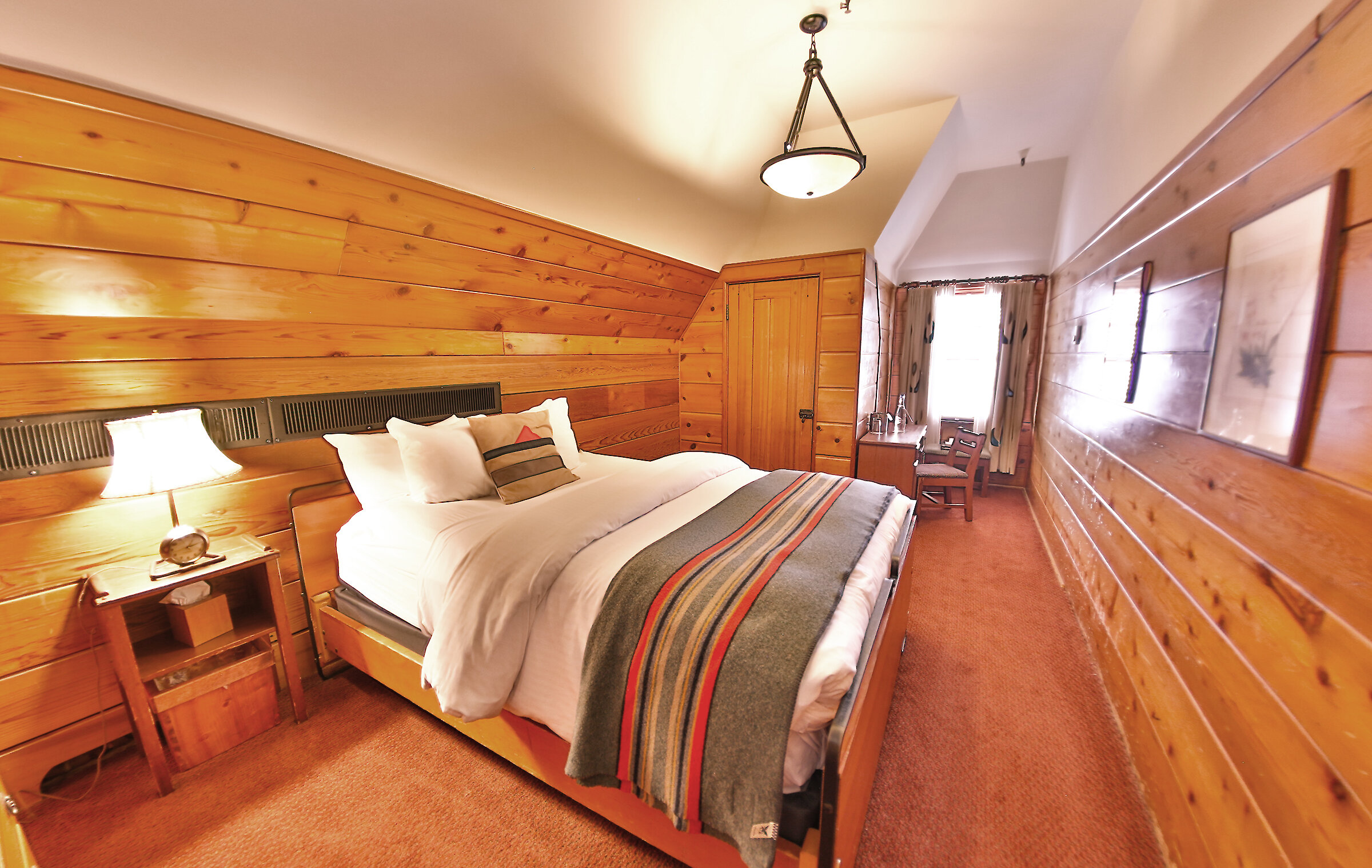 A Timberline queen room pictured with a Pendleton blanket draped over it.