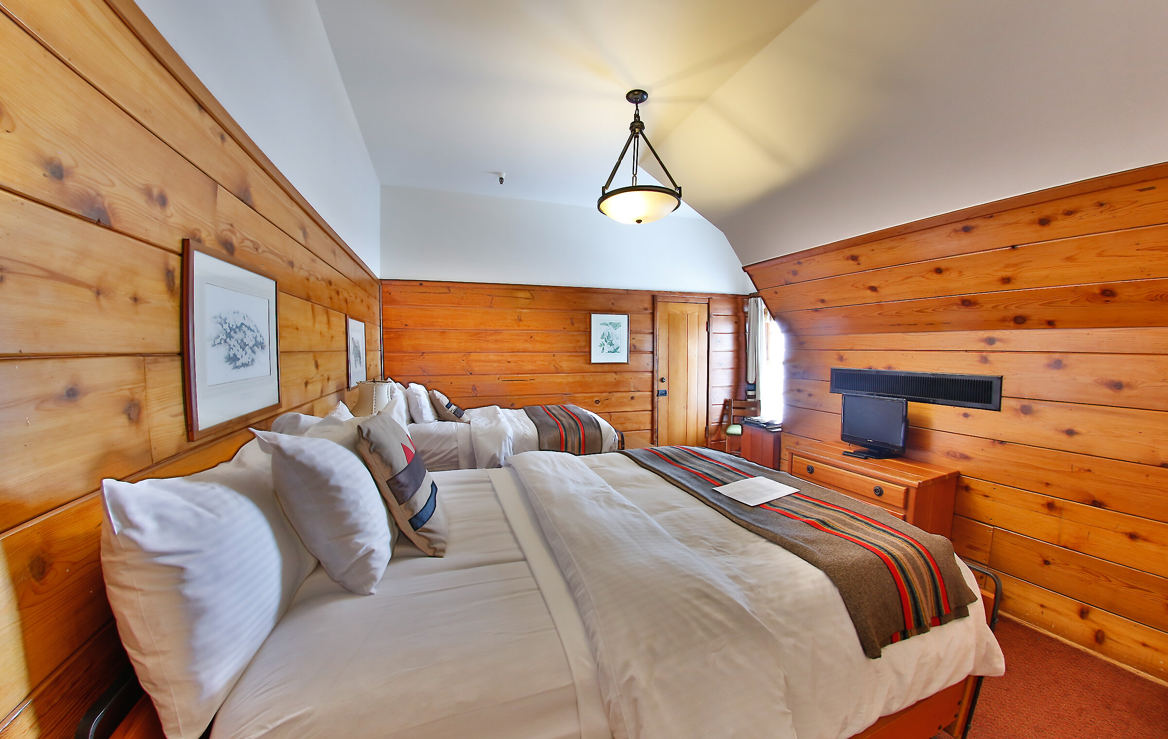 A Timberline queen + twin room pictured with a Pendleton blankets draped over the beds and wood-paneled walls.