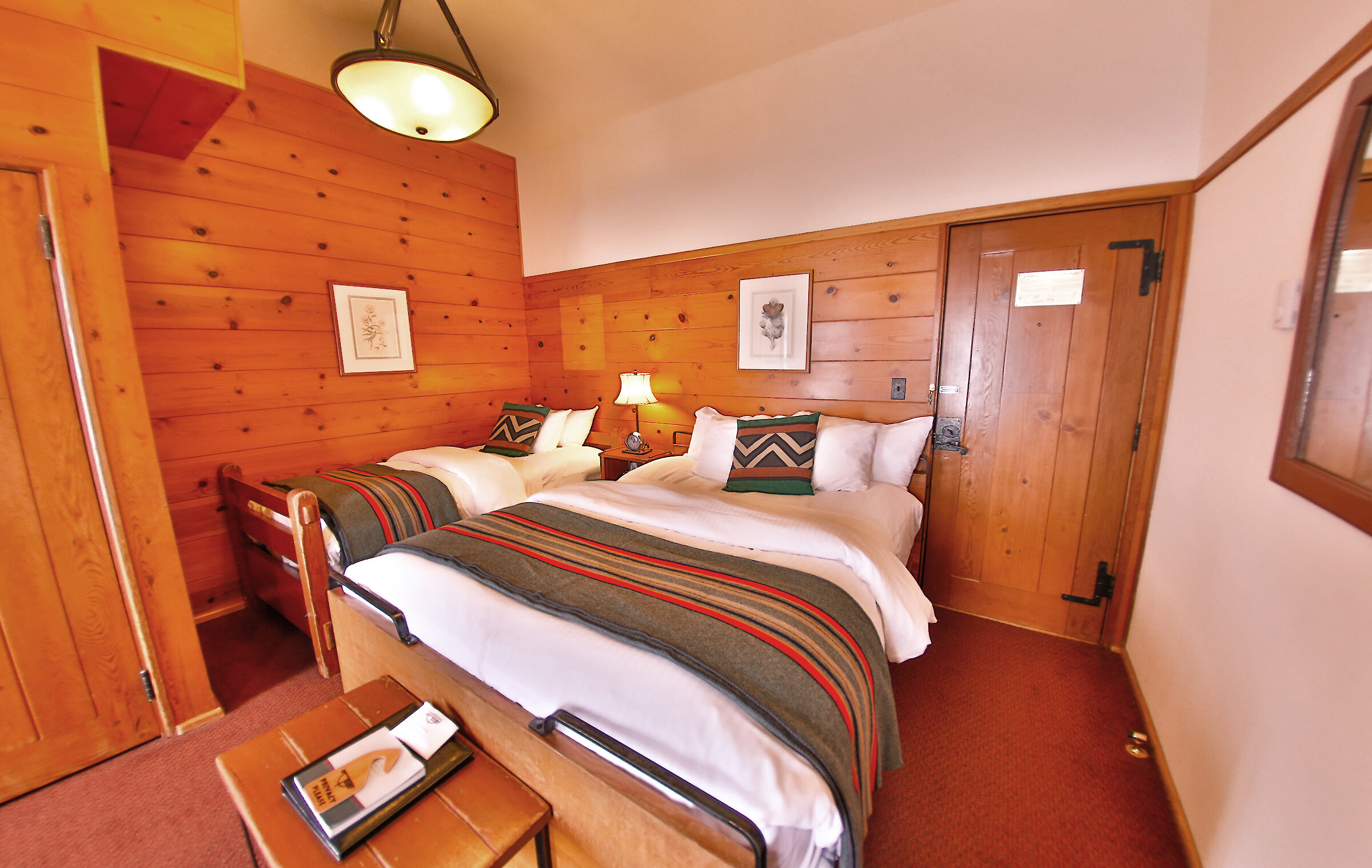 A Timberline queen + twin room pictured with a Pendleton blankets draped over the beds and wood-paneled walls.