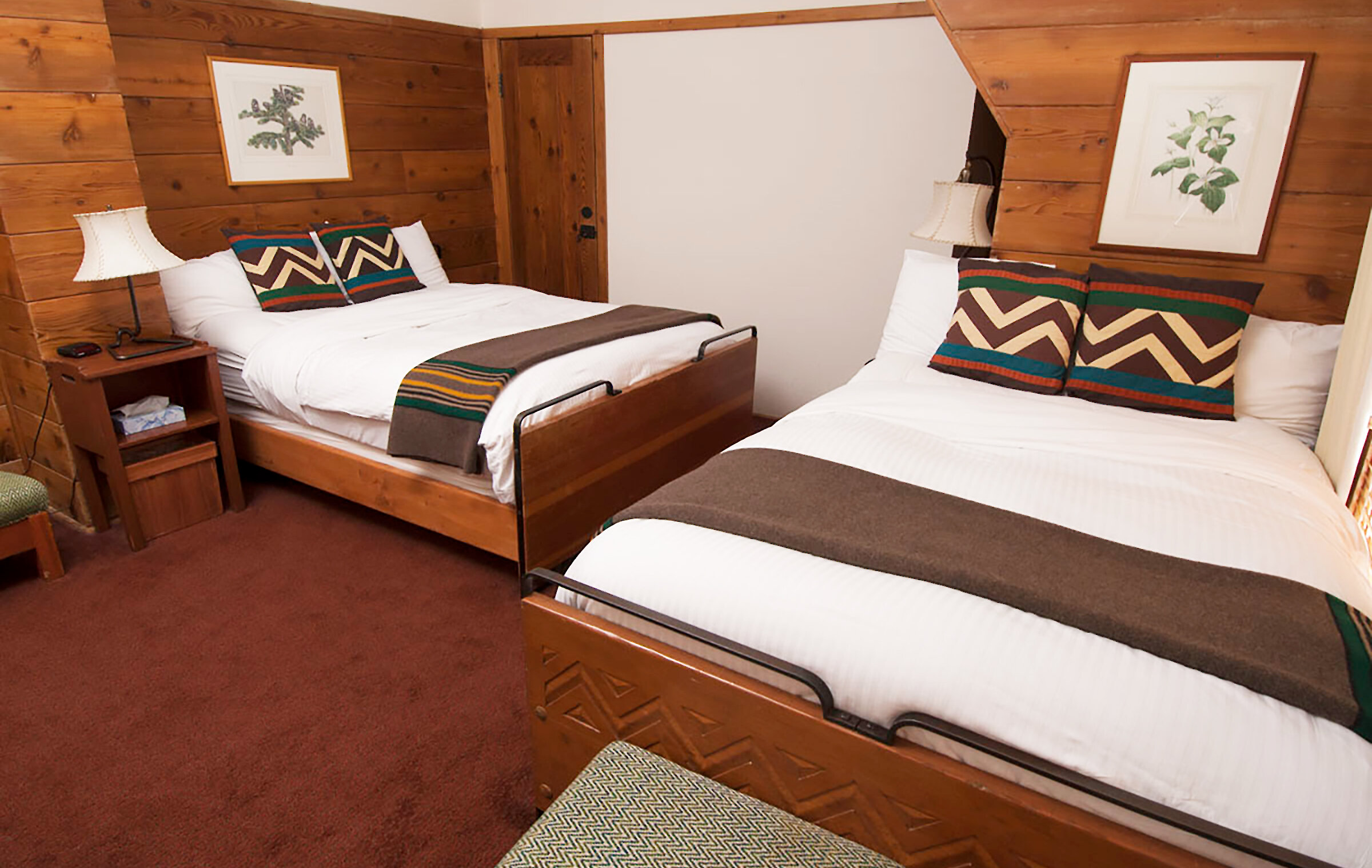A Timberline queen + double room pictured with a Pendleton blankets draped over the beds and wood-paneled walls.